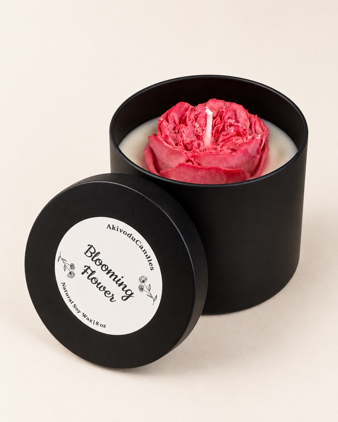 Black candle tin with a pink flower-shaped wax centerpiece and labeled lid.